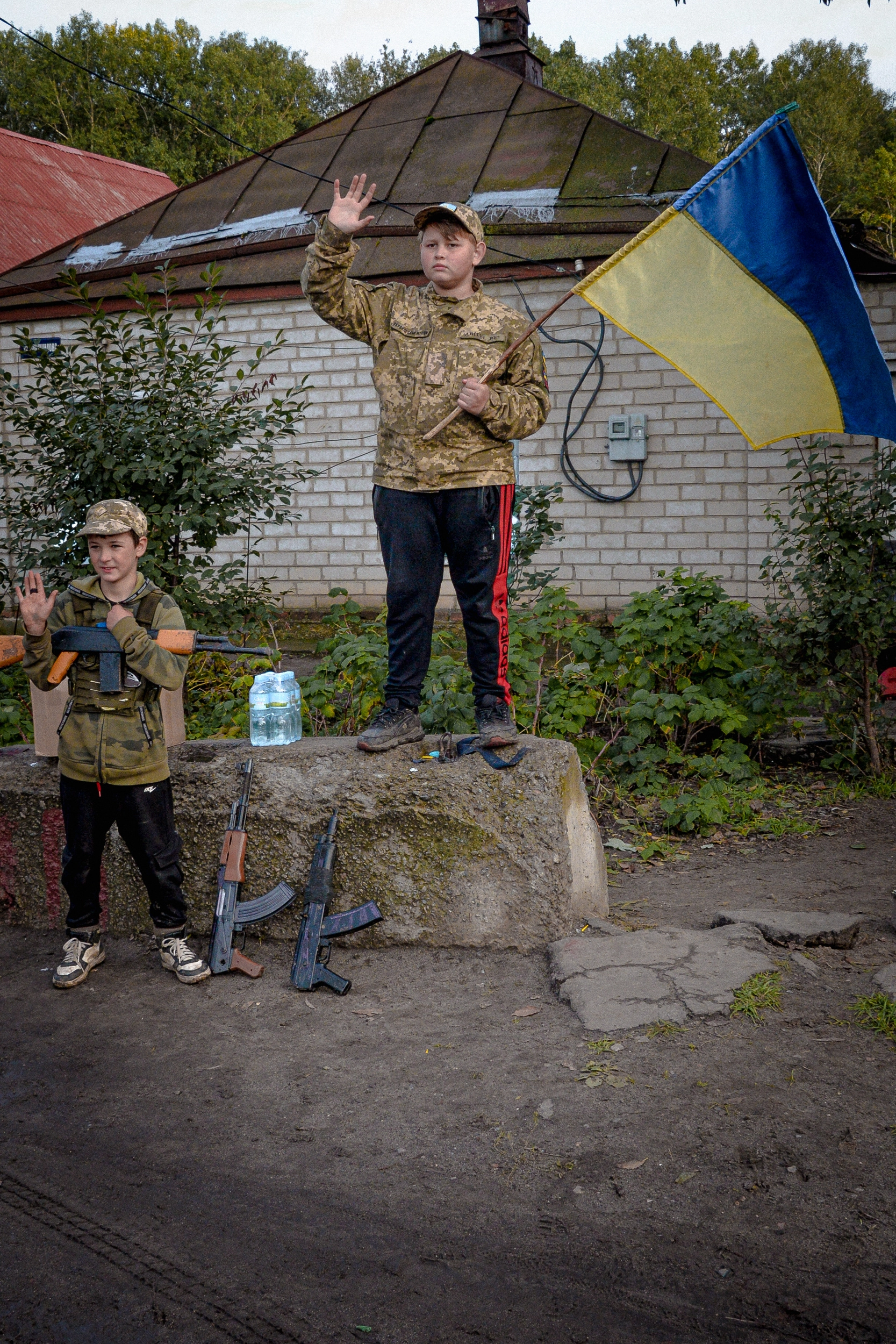 Двоє хлопчиків у містечку Чугуїв Харківській області махають з узбіччя водіям, що проїжджають повз. Вони сказали кореспонденту Kyiv Post, що хочуть показати людям, що мешканці Чугуєва, нещодавно звільненого від російської окупації, віддані Україні. Фото Стефана Коршака, 24 вересня.