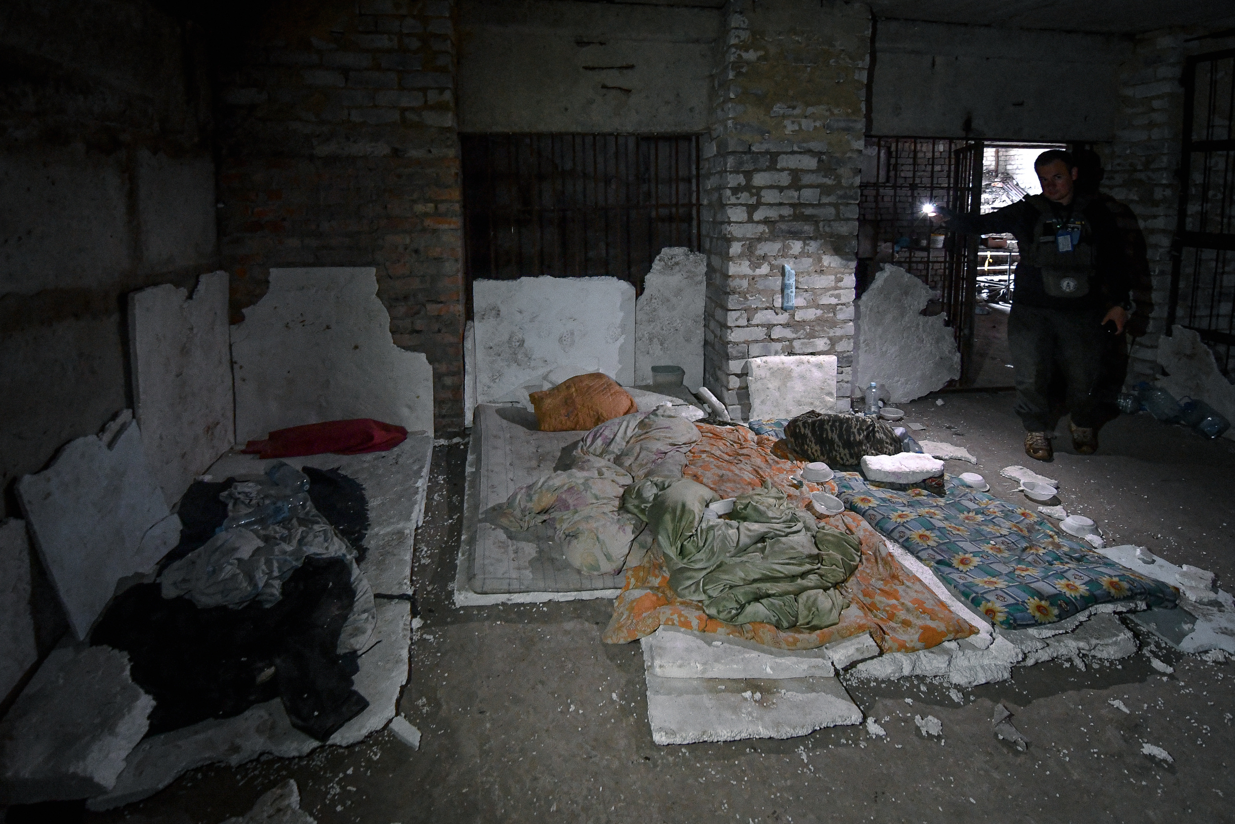 Ватажок команди харківських волонтерів Микола Зинов’єв (справа) в підвалі будівлі в селищі Козача Лопань, показує, на чому спали люди, яких тут тримали росіяни.