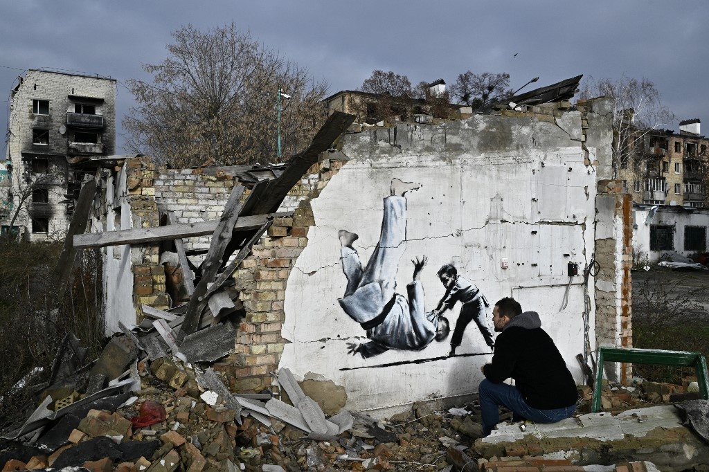 A local resident looks graffiti on the wall of a destroyed building in Borodyanka.
