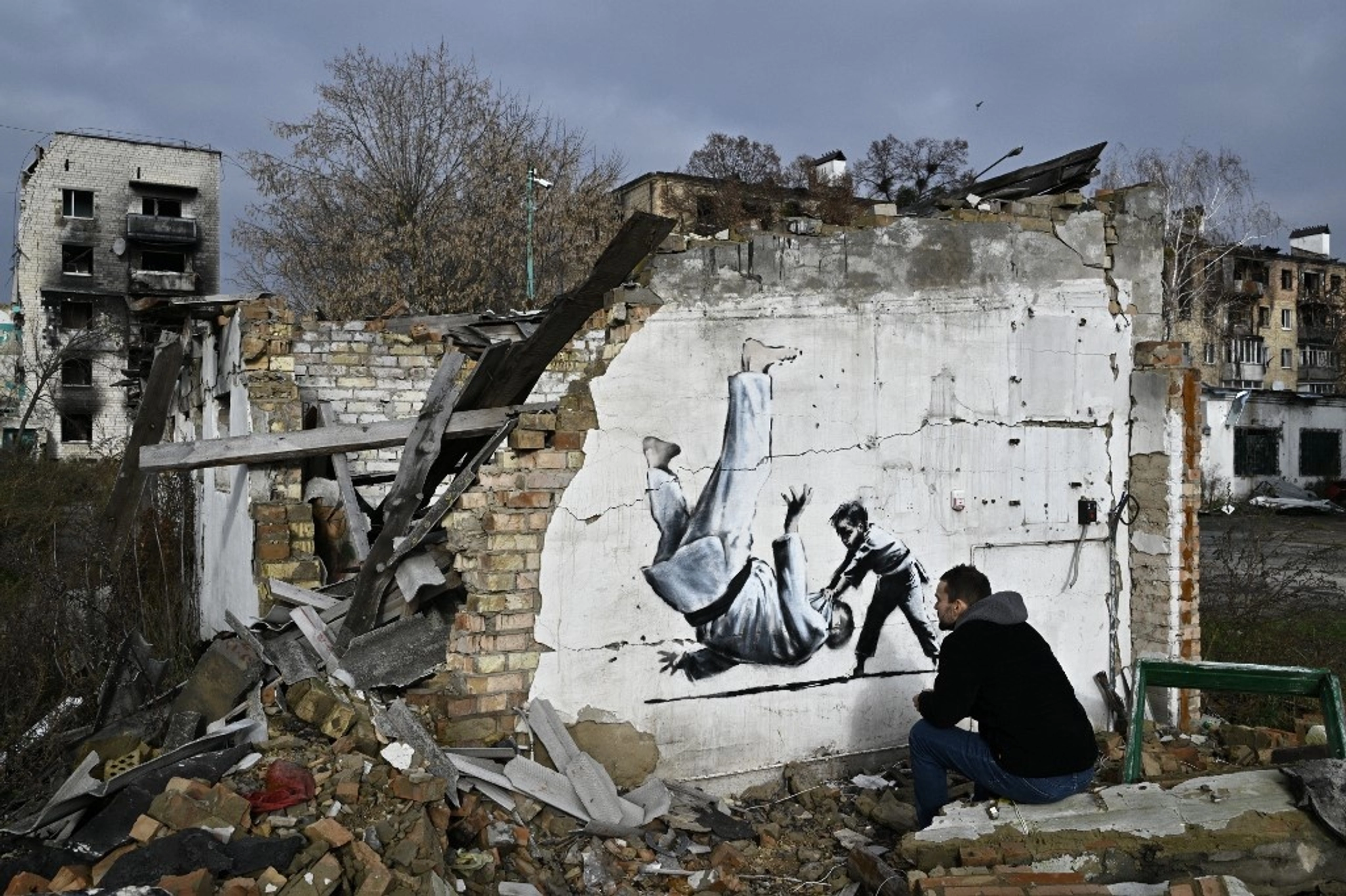 A local resident looks graffiti on the wall of a destroyed building in Borodyanka.