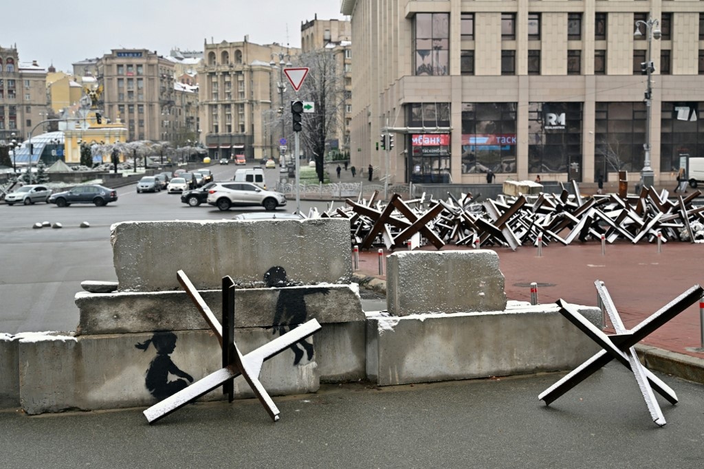 This photograph taken on November 17, 2022, shows a piece by British street artist Banksy on an anti-tank constructions at Independence Square in Kyiv.