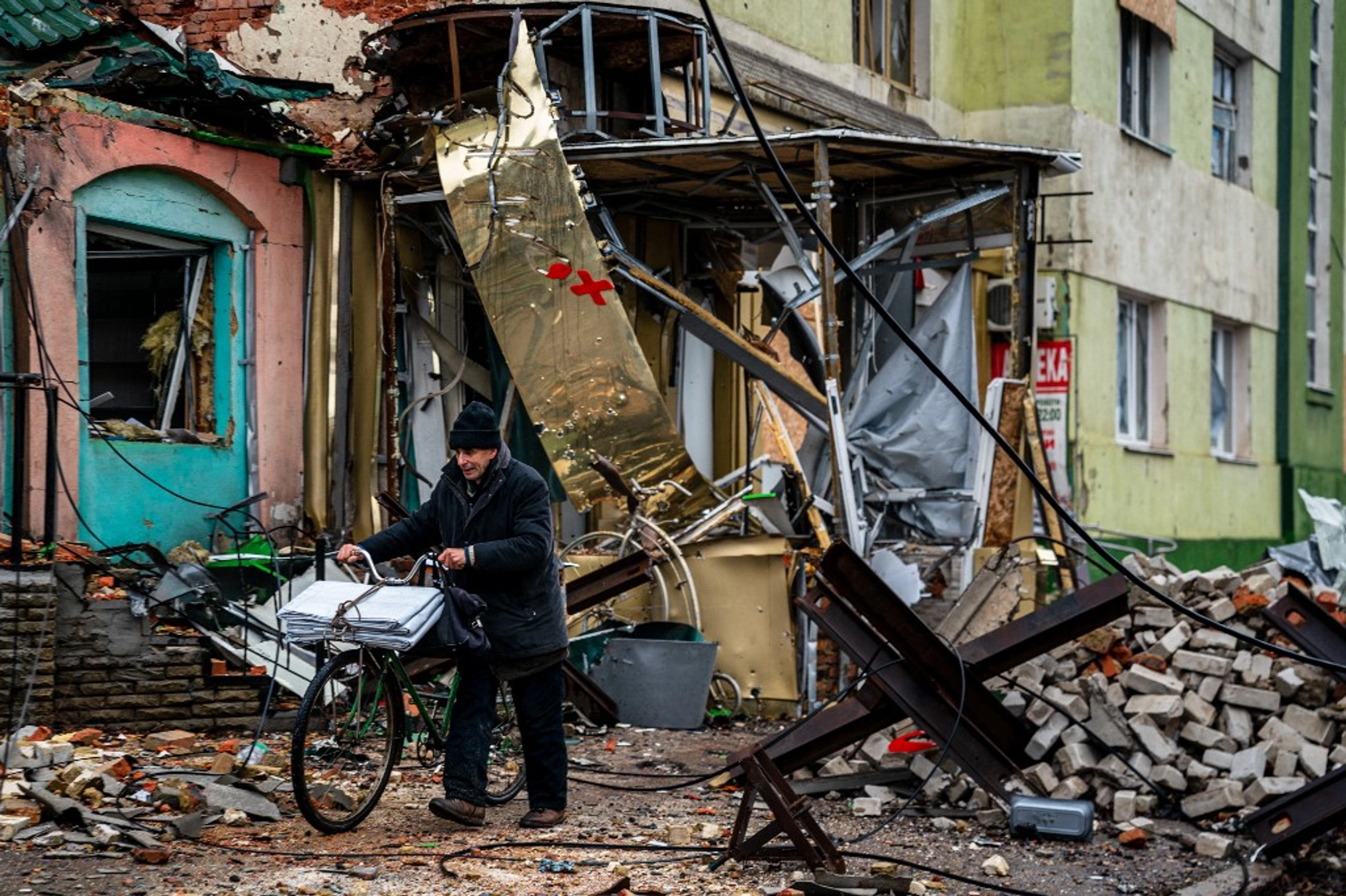 A local resident pushes his bicycle past "hedgehog" tank traps and rubble, down a street in Bakhmut, Donetsk region, on January 6, 2023. AFP