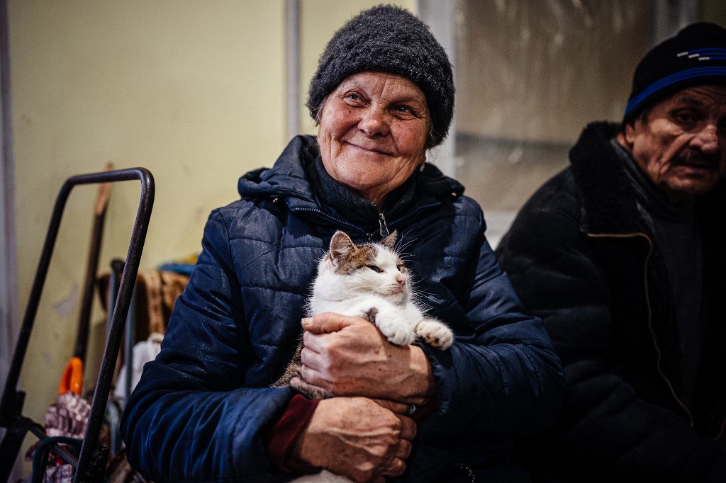 A local resident holds her cat as she sits in a humanitarian aid centre in Bakhmut, Donetsk region, on January 6, 2023. AFP