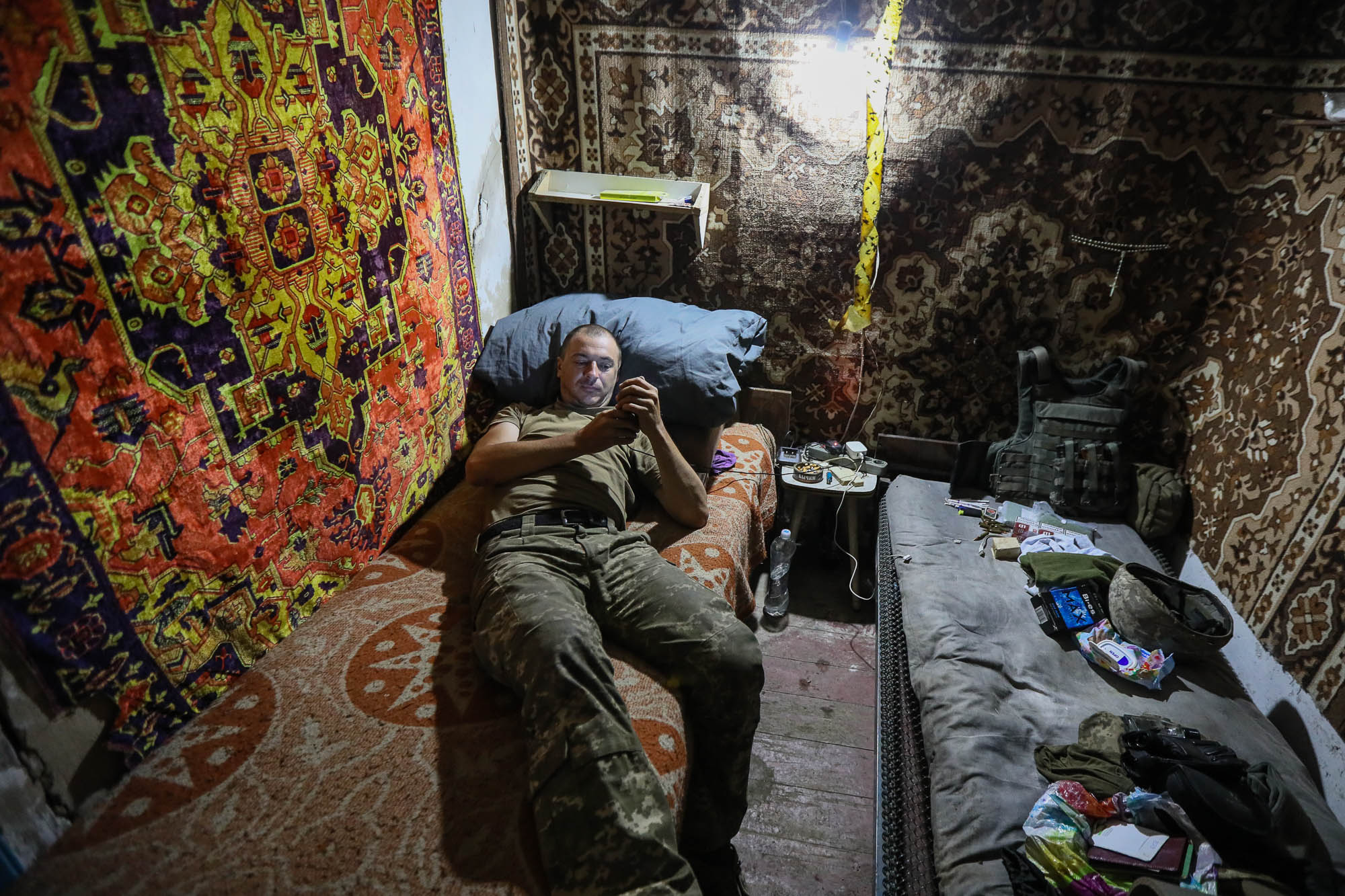 A Ukrainian soldier chats on Facebook on his smartphone as he rests after his combat duty in an accommodated basement of a ruined civilian house in the town of Zaitseve on June 25 