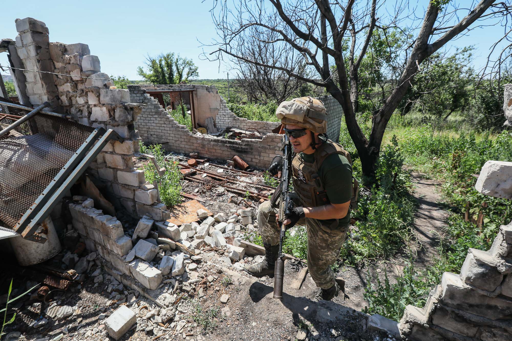 A Ukrainian soldier walks among the ruins of a shelled house as he scouts the combat area in the town of Zaitseve on June 25