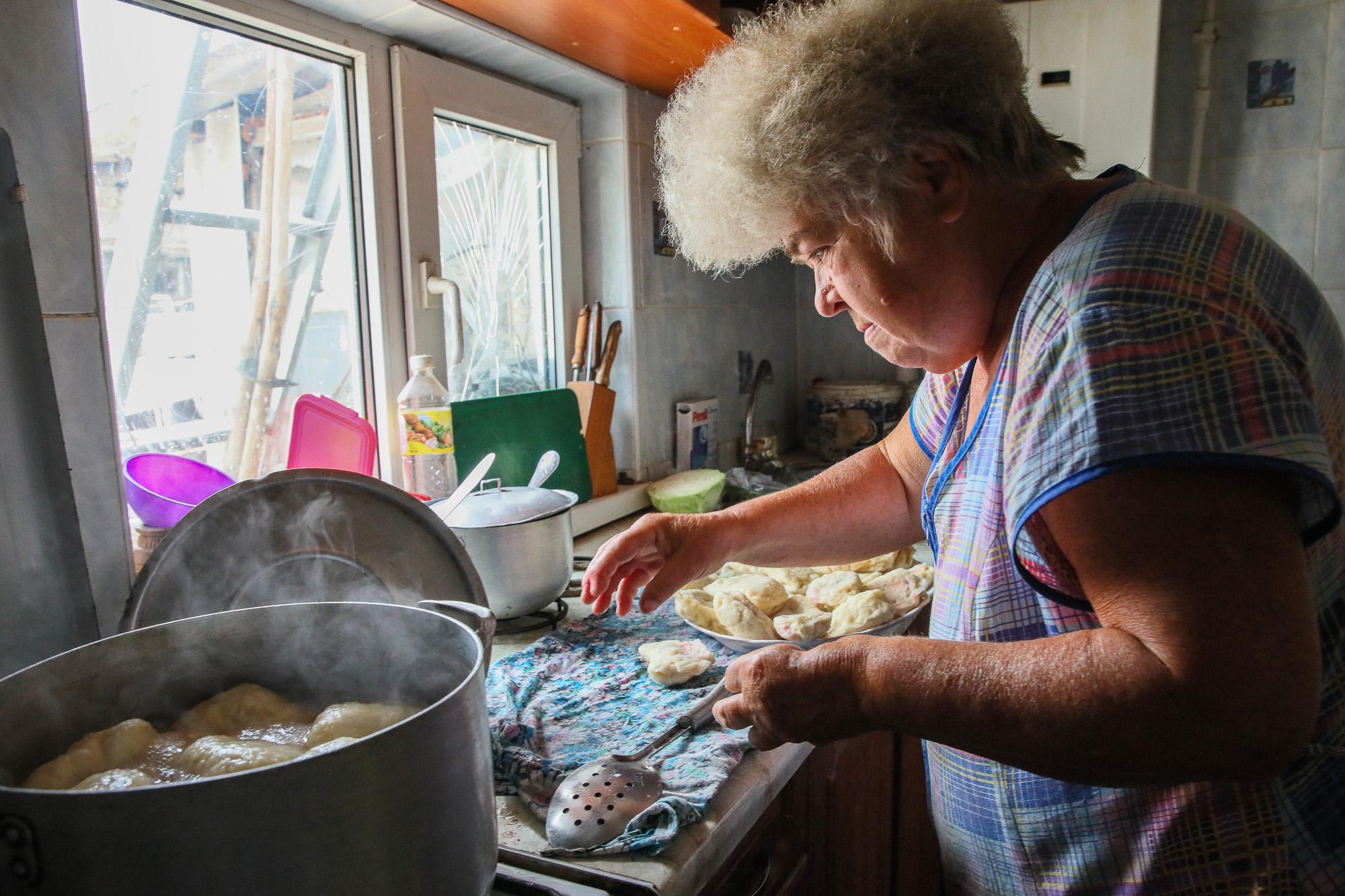 Anna Goncharova, a local civilian, cooks cherry dumplings on a gas stove at her home in the town of Opytne on June 12, 2019.