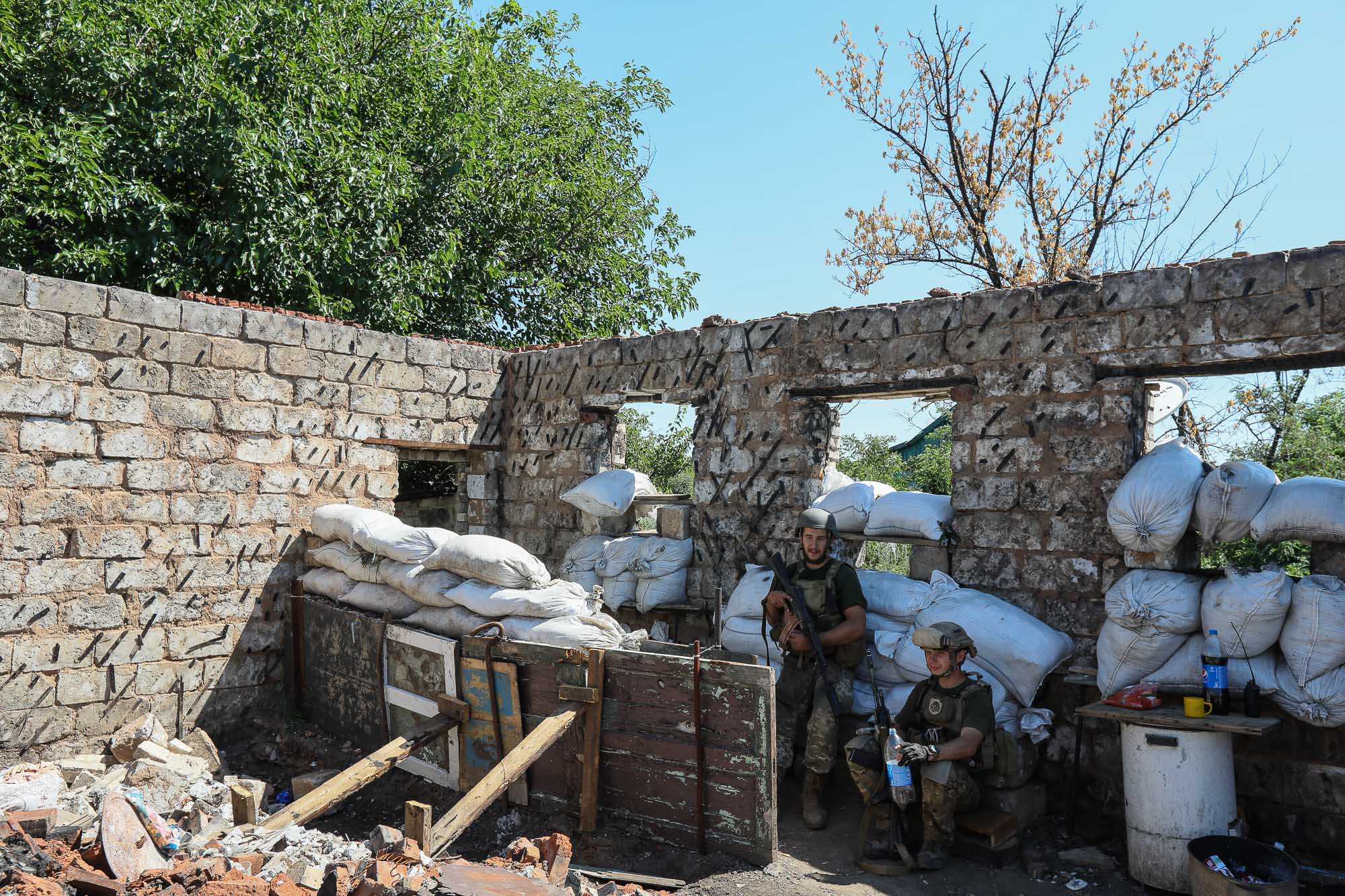 Ukrainian soldiers drink water as they draw their combat duty in the town of Zaitseve on June 25