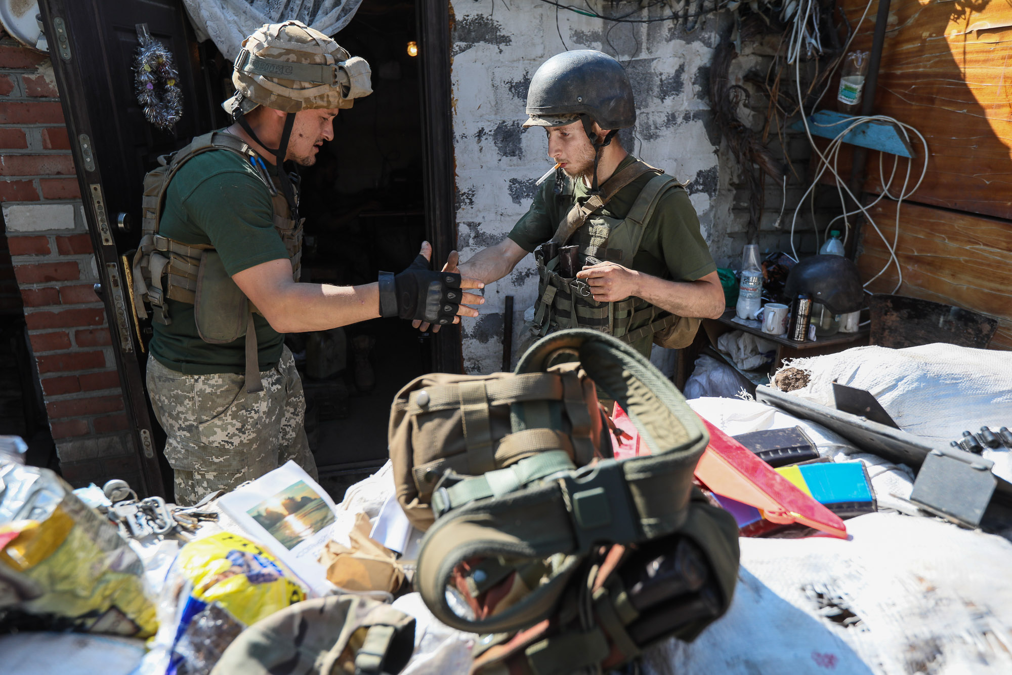 Ukrainian soldiers shake hands as they greet each other at a combat post in the town of Zaitseve on June 25