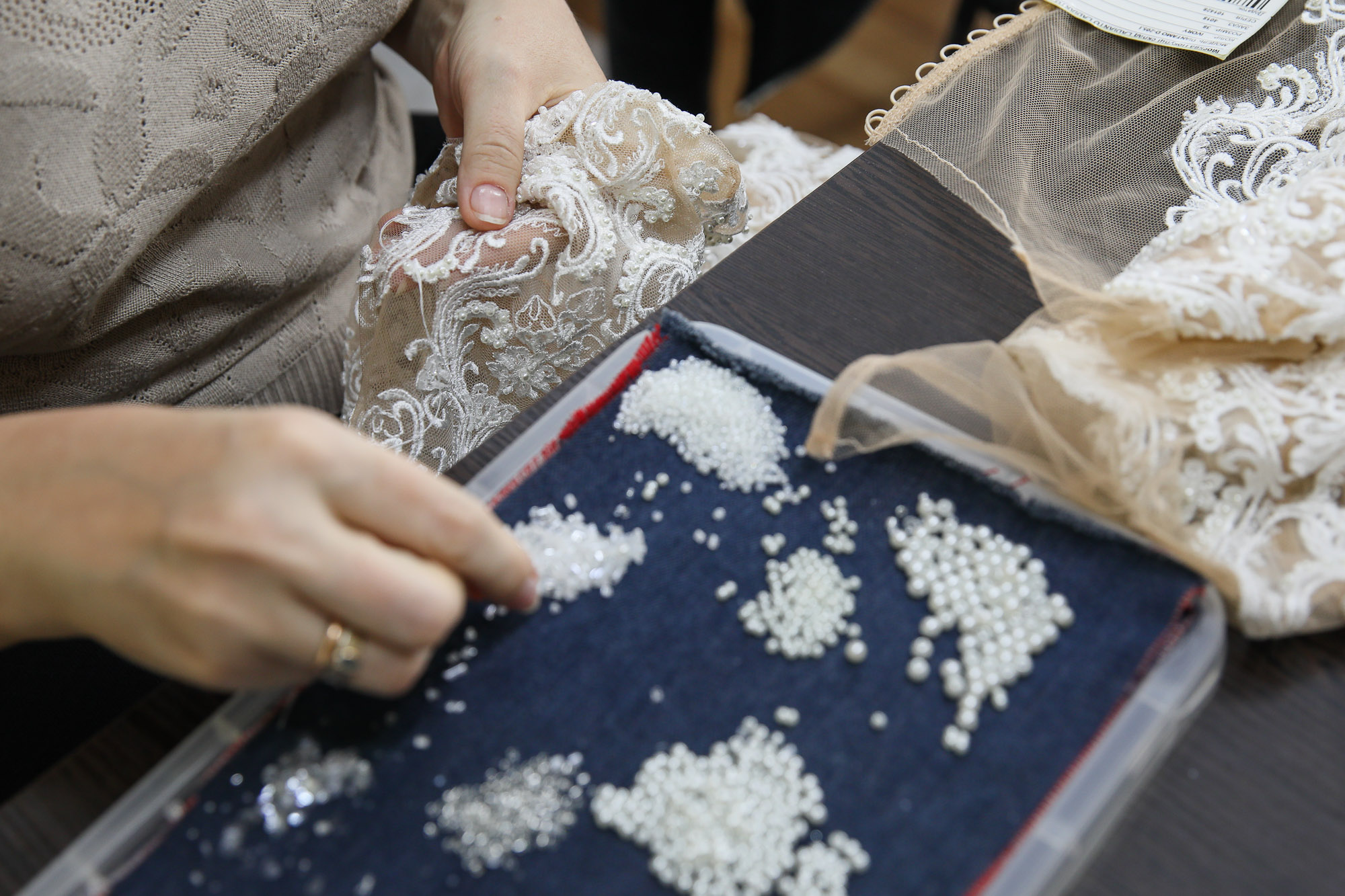 A seamstress manually attaches decorative elements to a future wedding dress. (Volodymyr Petrov)