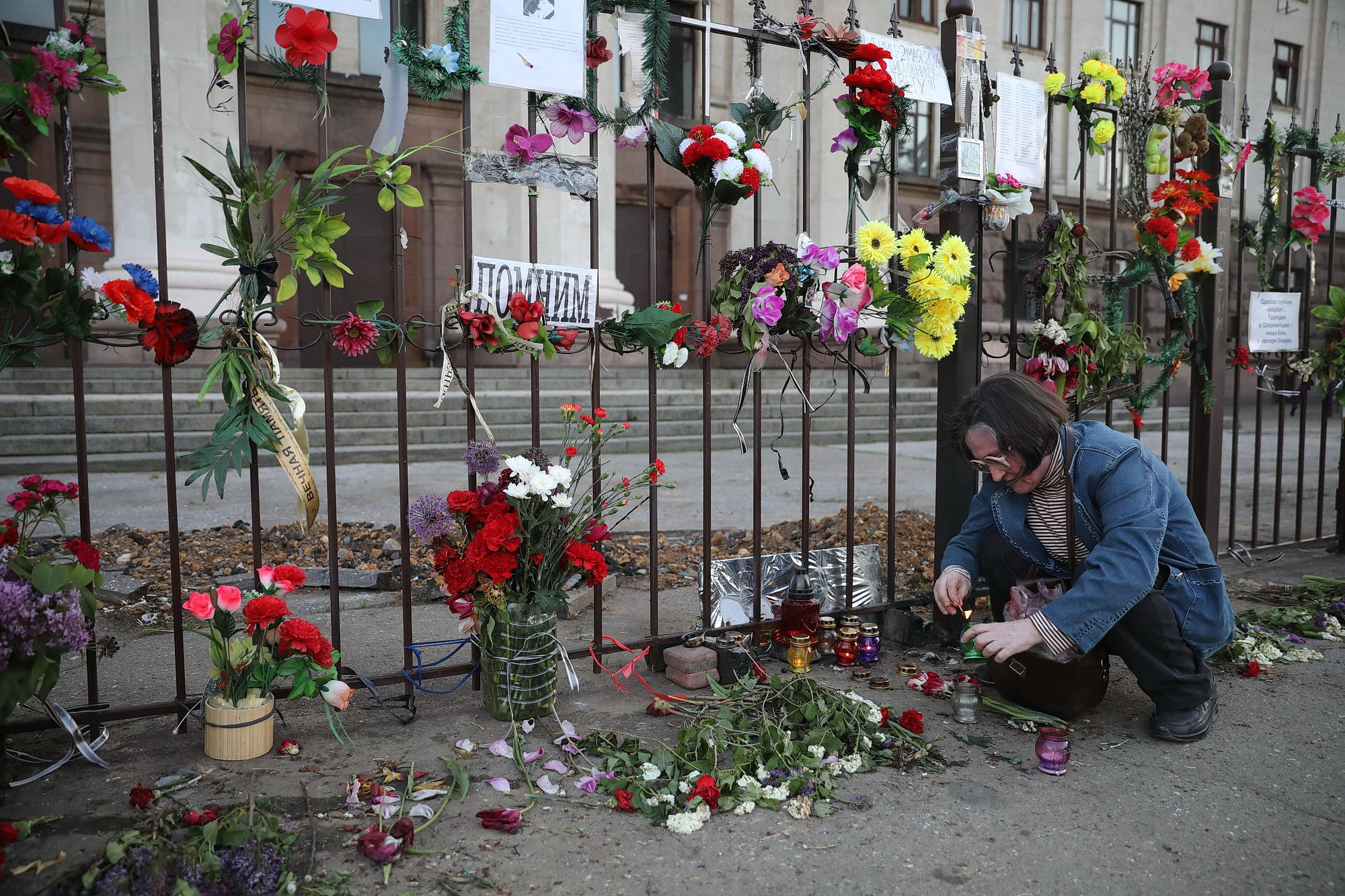 Pro-Russian activist Vera Butuk lits candles by the gate surrounding the Trade Unions House in Odesa on May 12, 2019, in remembrance of 42 people, who died from the fire there on May 2, 2014. The 48 people were killed in Odesa on that day as a result of the fire and street fights between pro-Russian and pro-Ukrainian activists.