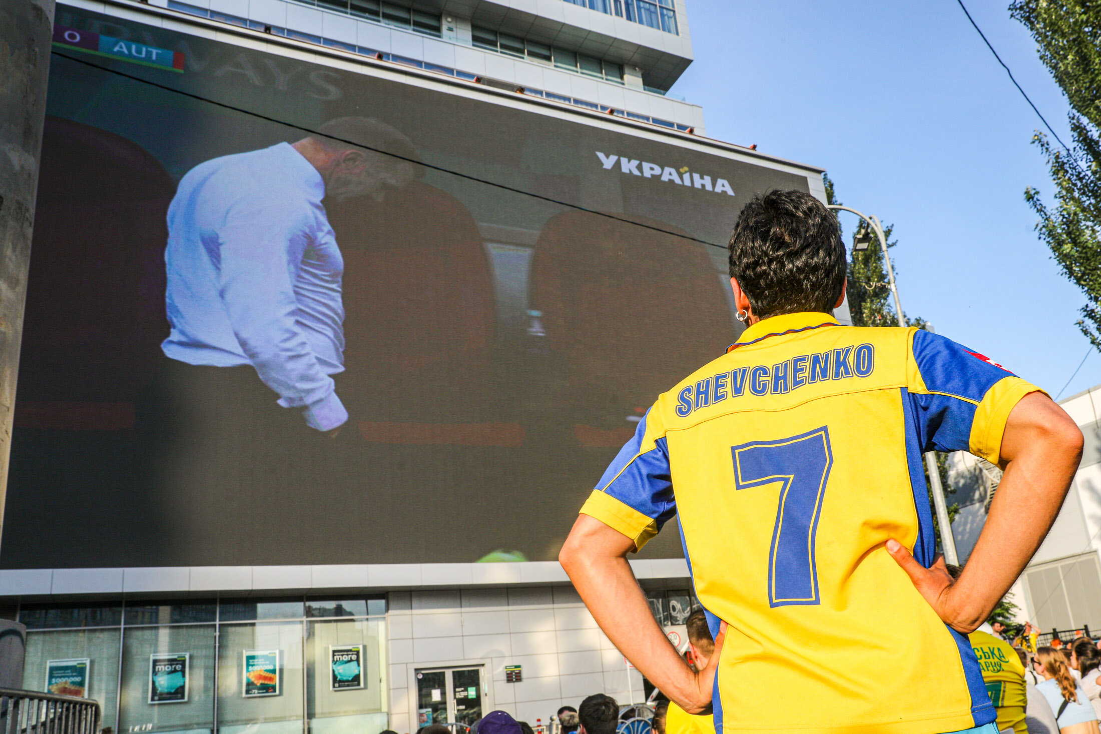 Ukrainian supporter llooks at Andrii Shevchenko, coach of the Ukrainian National team, as he watch the UEFA EURO 2020 Group C football match between Ukraine and Austria on a giant screen in the center of Kyiv on June 21, 2021.