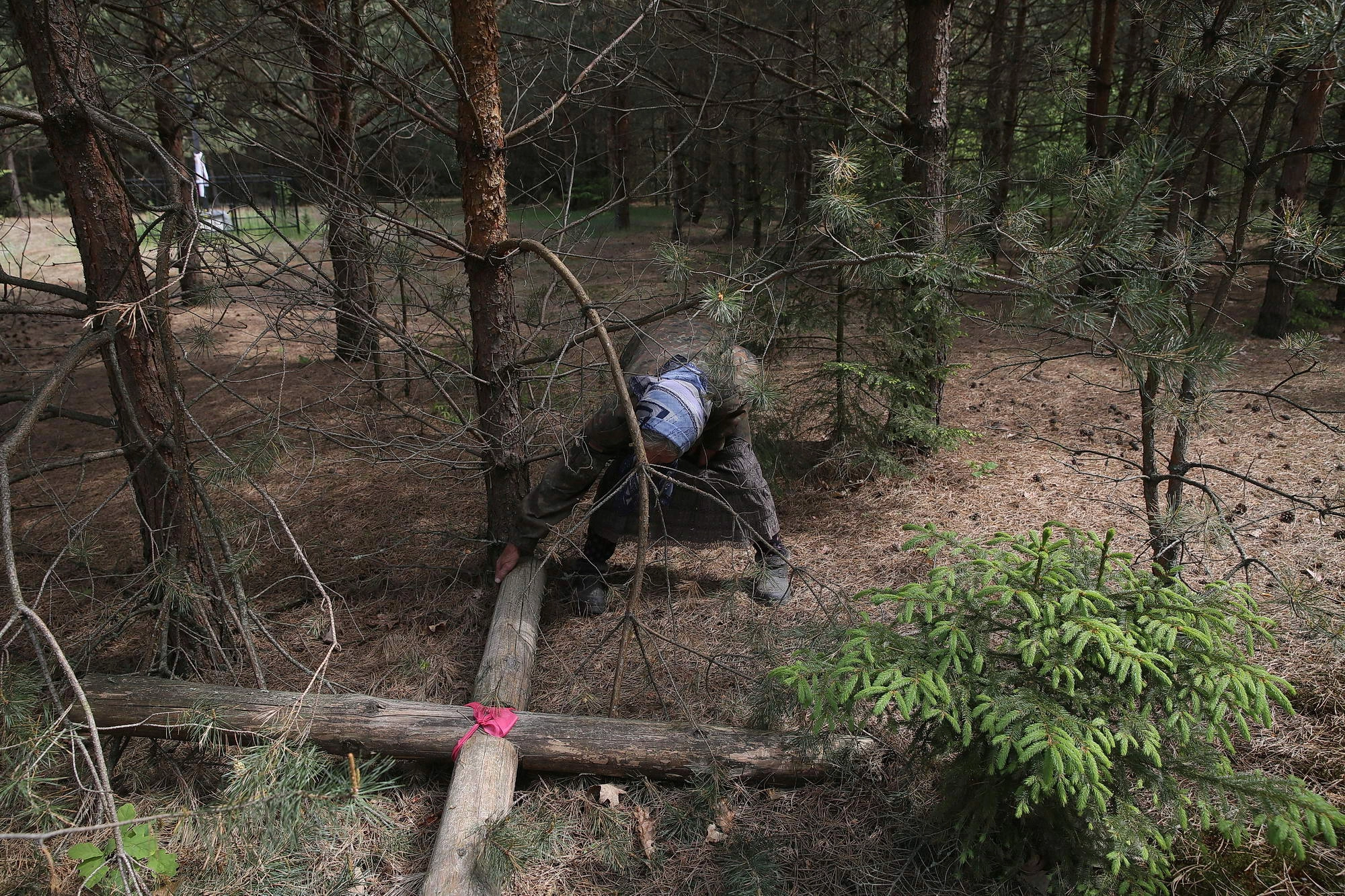 Oleksandra Vaseiko touches a fallen cross that was hoisted at the place, where hundreds of Poles were killed in 1943.