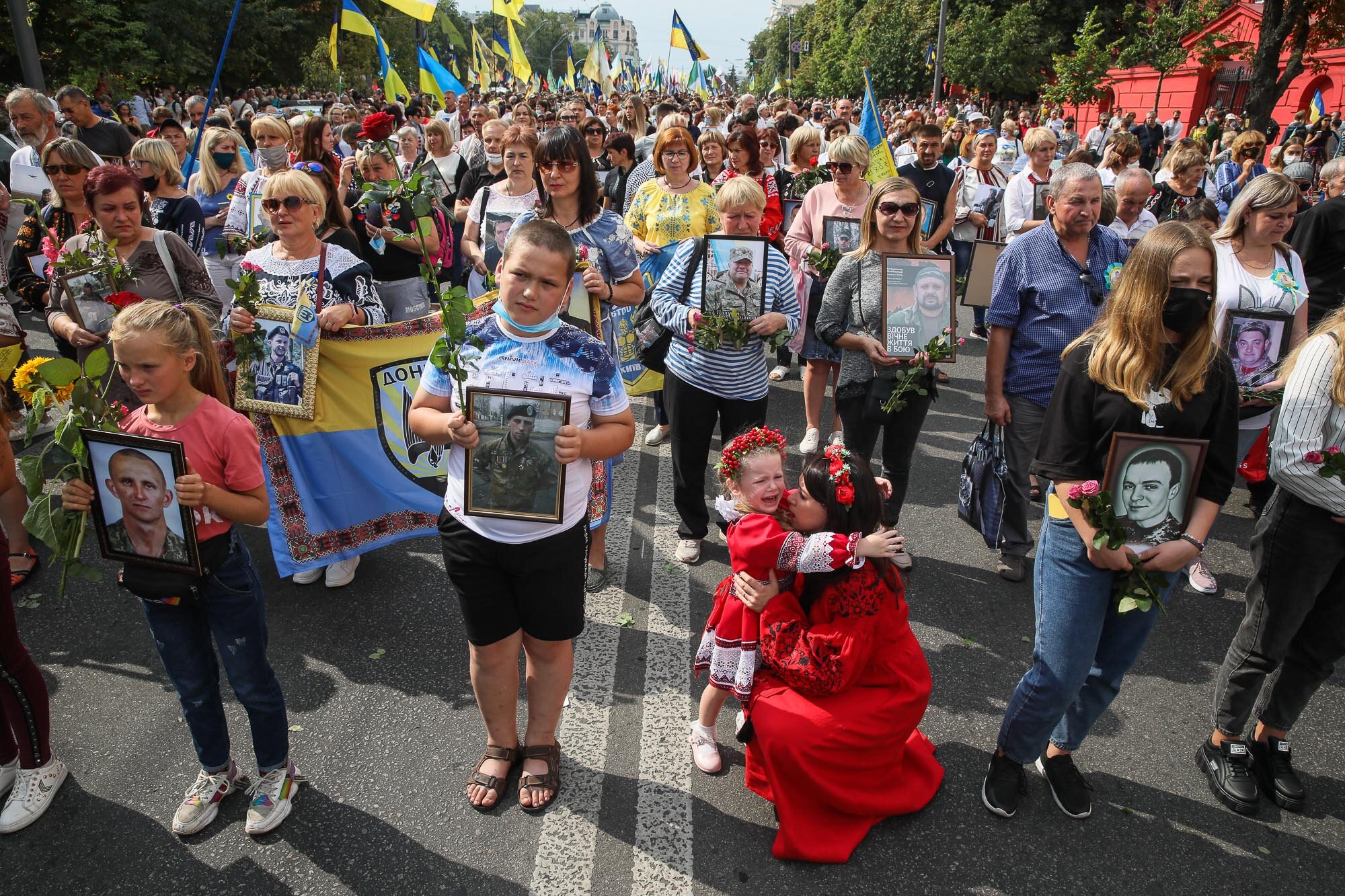 A girl cries as relatives carry portraits of fallen soldiers during the March of Defenders of Ukraine, an event where participants marched in downtown Kyiv as part of Ukraine&#8217;s Independence Day celebrations on Aug. 24, 2020.