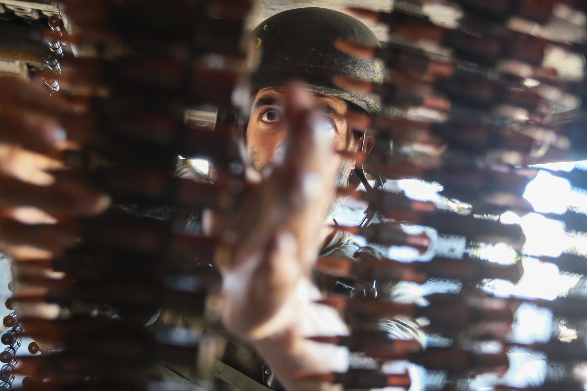 A Ukrainian soldier tapes up machine gun cartridge belt in a dugout in the combat zone of Zaitseve on June 25 