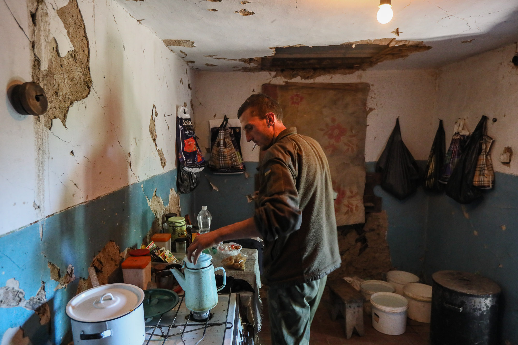 A Ukrainian soldier boils water for tea in a kitchen of an abandoned house in the frontline town of Zaytseve, eastern Ukraine, on June 25, 2018.