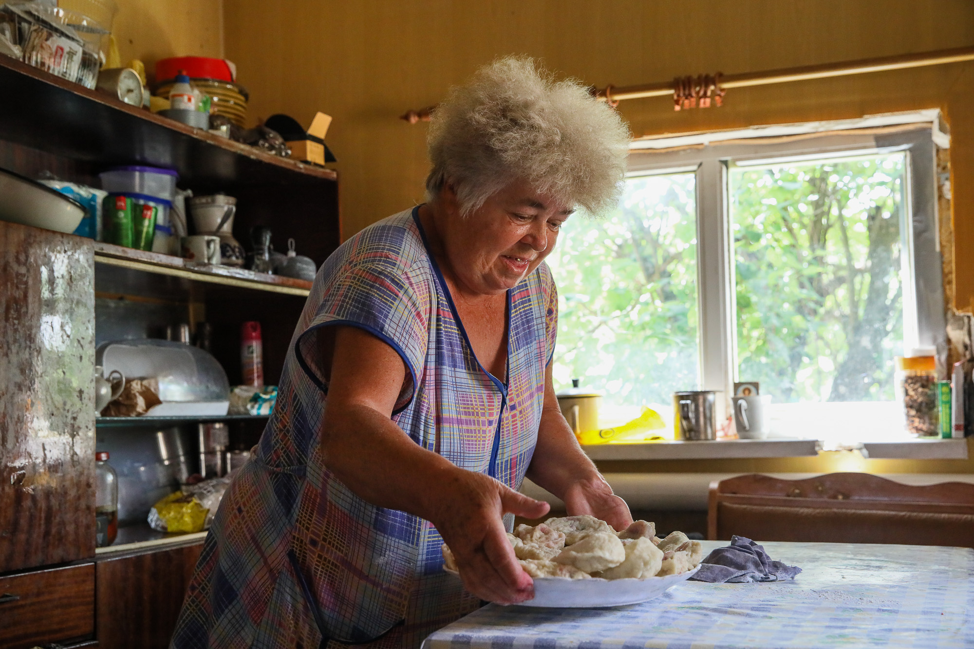 Anna Goncharova, a local civilian, serves cherry dumplings for guests at her home in the town of Opytne on June 12, 2019.