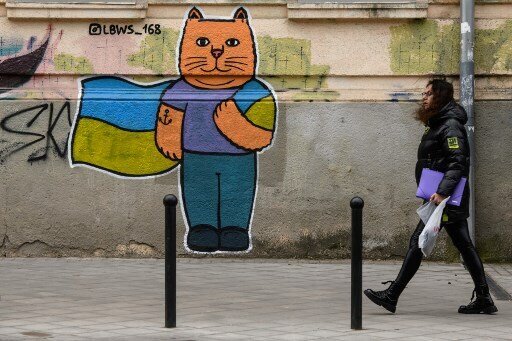 A woman walks in front of a street art creation by the LBWS street art collective on a street in the port city of Odesa on April 13, 2022. (Photo by Ed JONES / AFP)