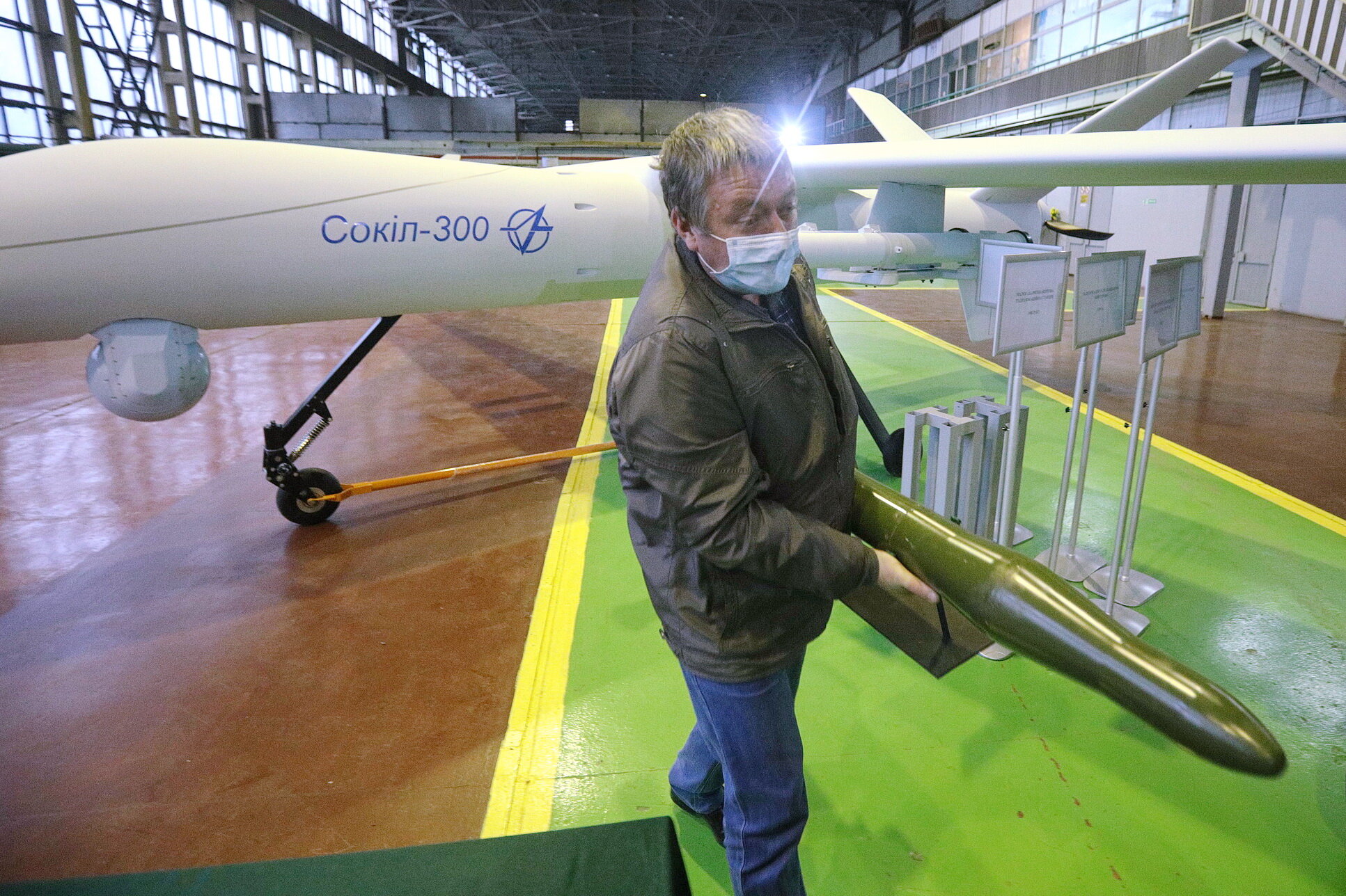 A worker carries a dummy missile next to strike drone system Sokil-300 mockup model pictured during a presentation in the city Vyshneve outside Kyiv on Nov. 6, 2020. 