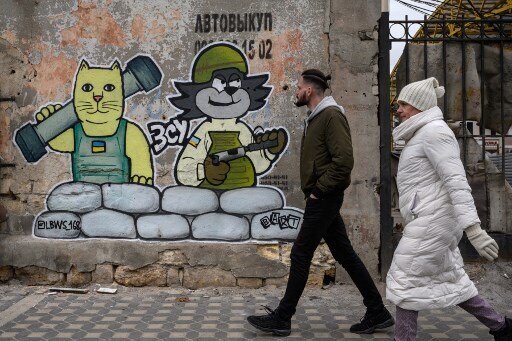 Pedestrians walk in front of a street art creation by the LBWS street art collective on a street in the port city of Odesa on April 13, 2022. (Photo by Ed JONES / AFP)