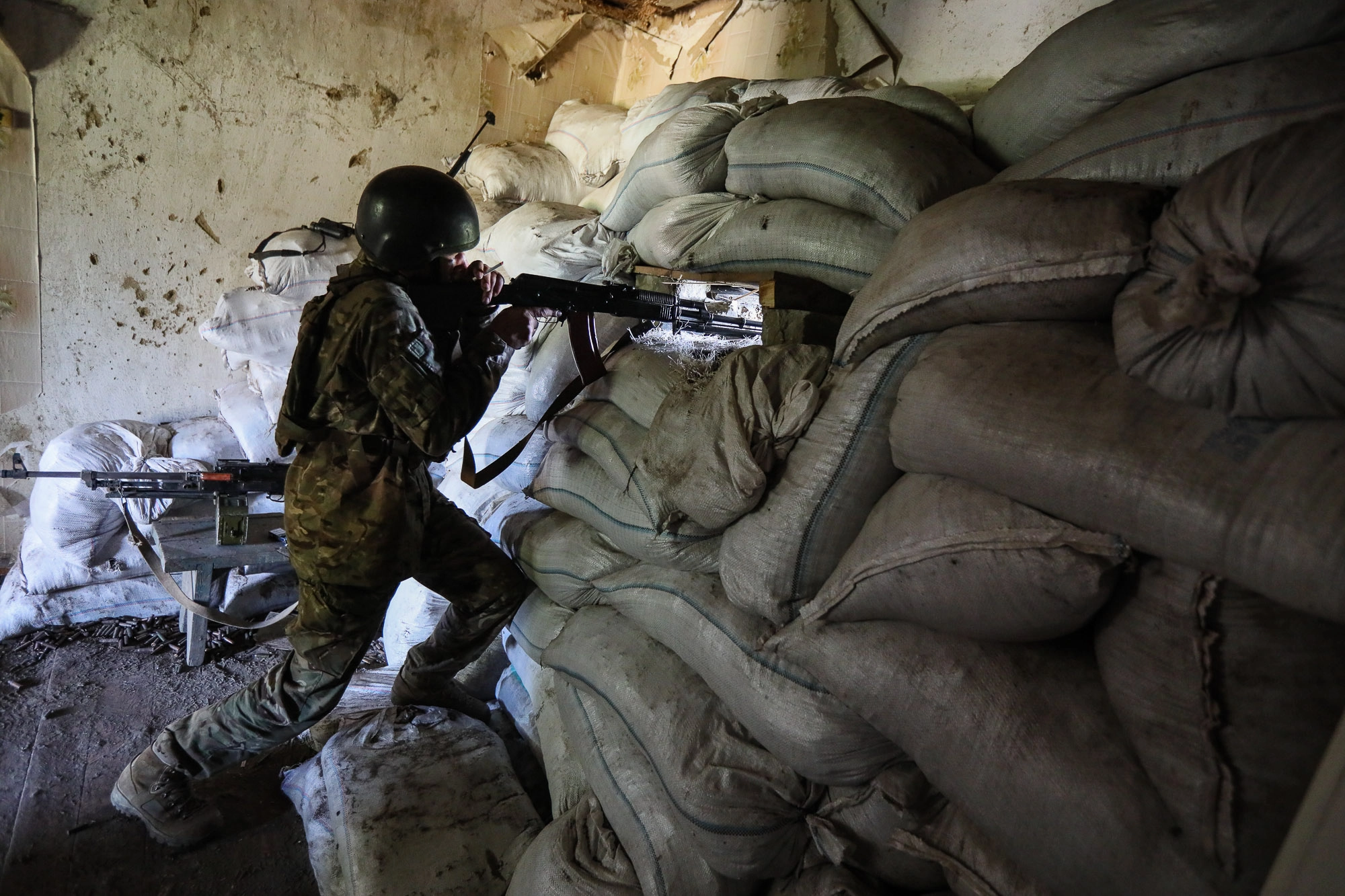 A Ukrainian soldier watches the enemy lines through a gunslot at a combat post in the town of Zaitseve, eastern Ukraine, on June 25, 2018. 