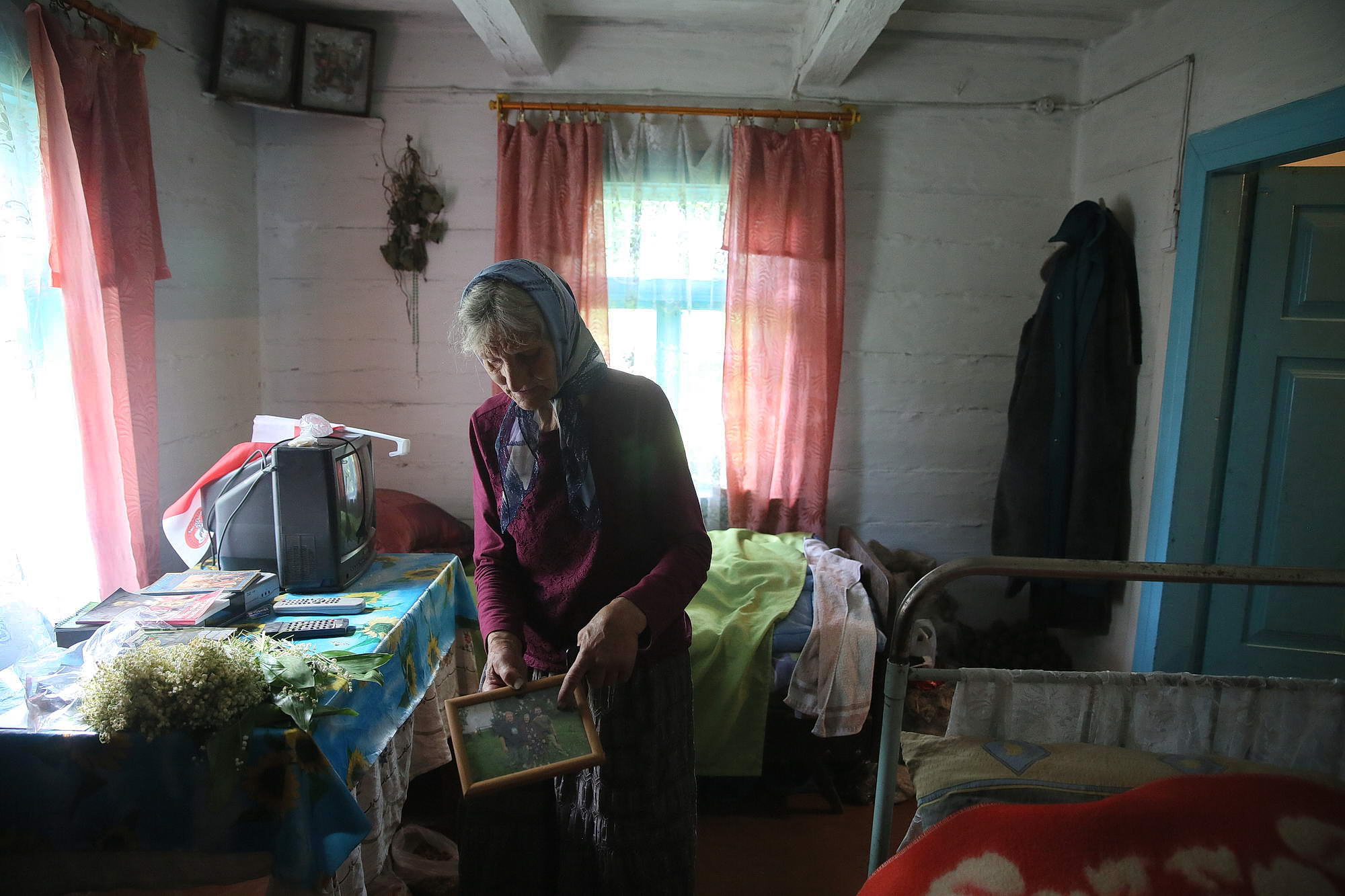 Oleksandra Vaseiko shows a photo of her with two Polish historians in her house in the village of Sokil in Volyn Oblast.