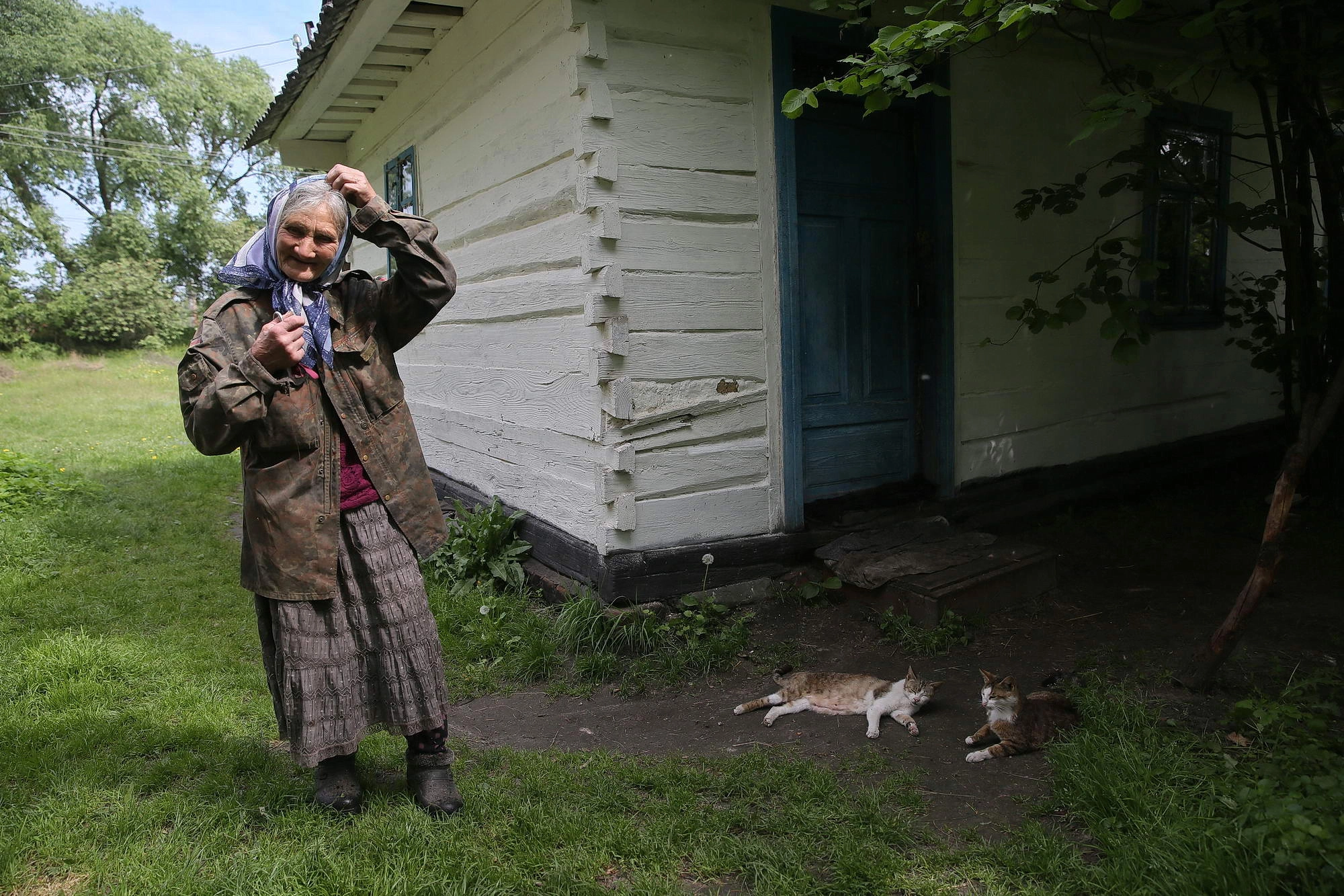 Oleksandra Vaseiko stands in her yard next to her cats in the village of Sokil in Volyn Oblast.