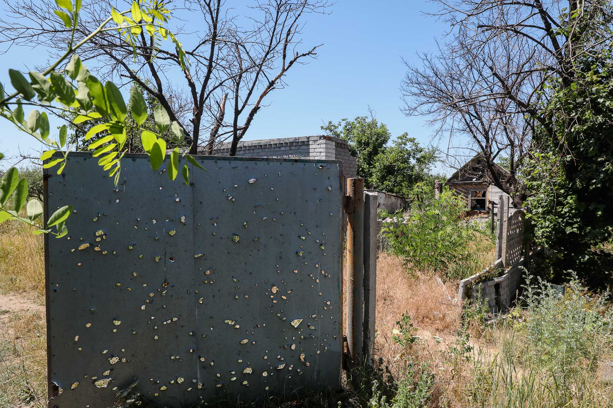 A part of metal fence densely riddled with shell fragments is seen in the frontline town of Zaitseve on June 25