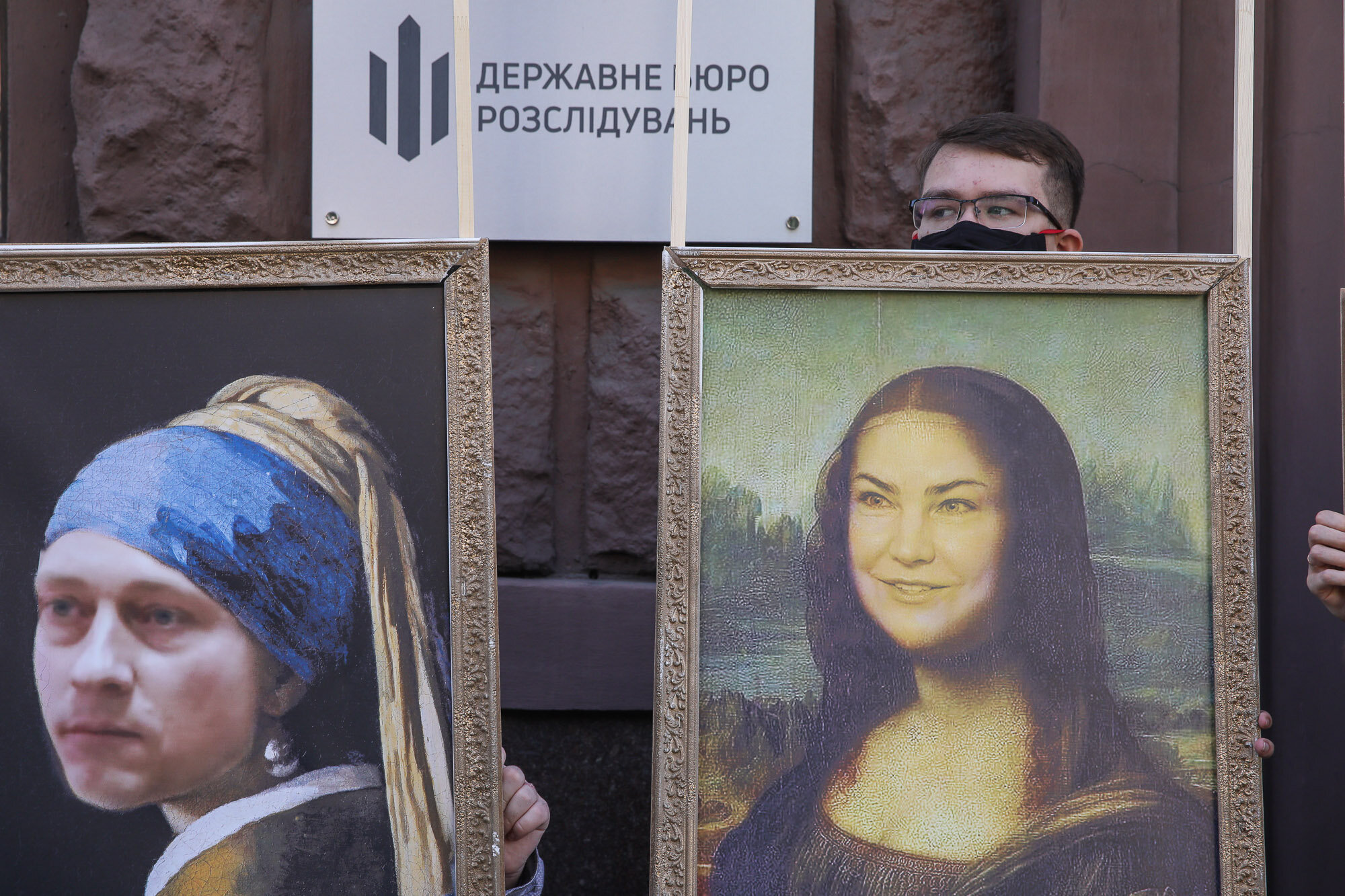 Activists and supporters of European Solidarity political party and Petro Poroshenko hold mockup pictures of classic art masterpieces with the faces of Prosecutor General Iryna Venediktova and President Volodymyr Zelensky during a rally in front of the State Investigation Bureau in downtown Kyiv on June 10, 2020.