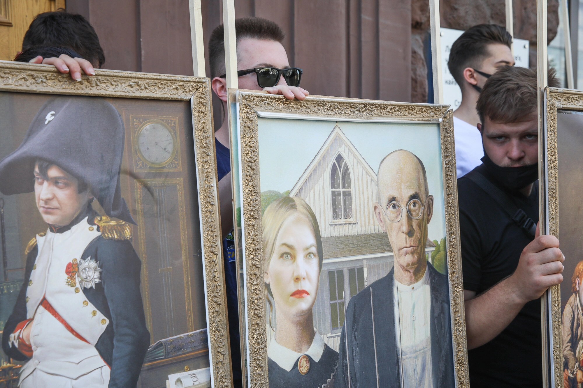 Activists and supporters of European Solidarity political party and Petro Poroshenko hold mockup pictures of classic art masterpieces with the faces of Prosecutor General Iryna Venediktova and President Volodymyr Zelensky during a rally in front of the State Investigation Bureau in downtown Kyiv on June 10, 2020.