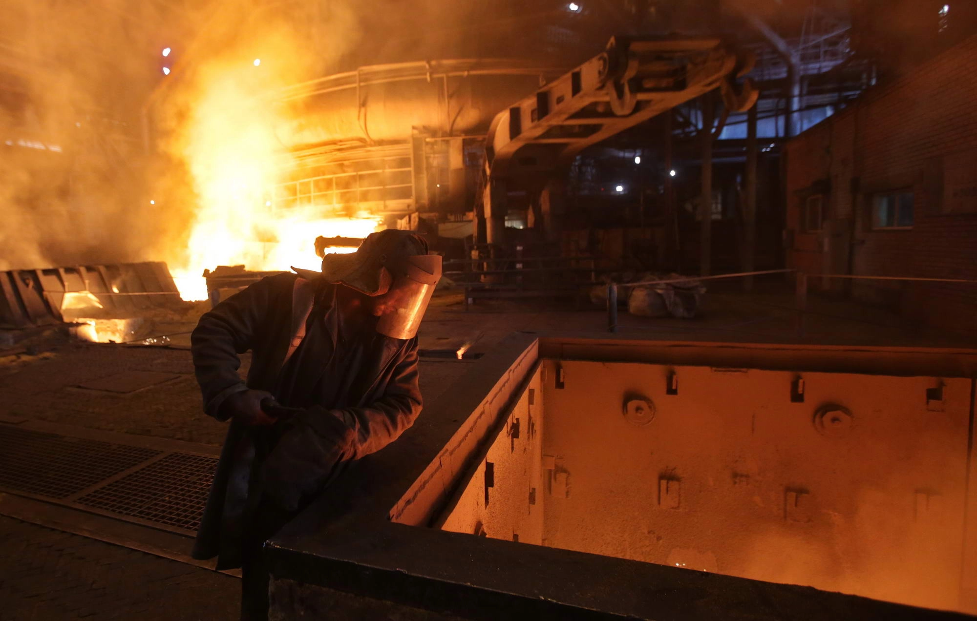 A steelworker inspects a flow of molten steel in a blast furnace at the ArcelorMittal Kryvyi Rih steel plant. 