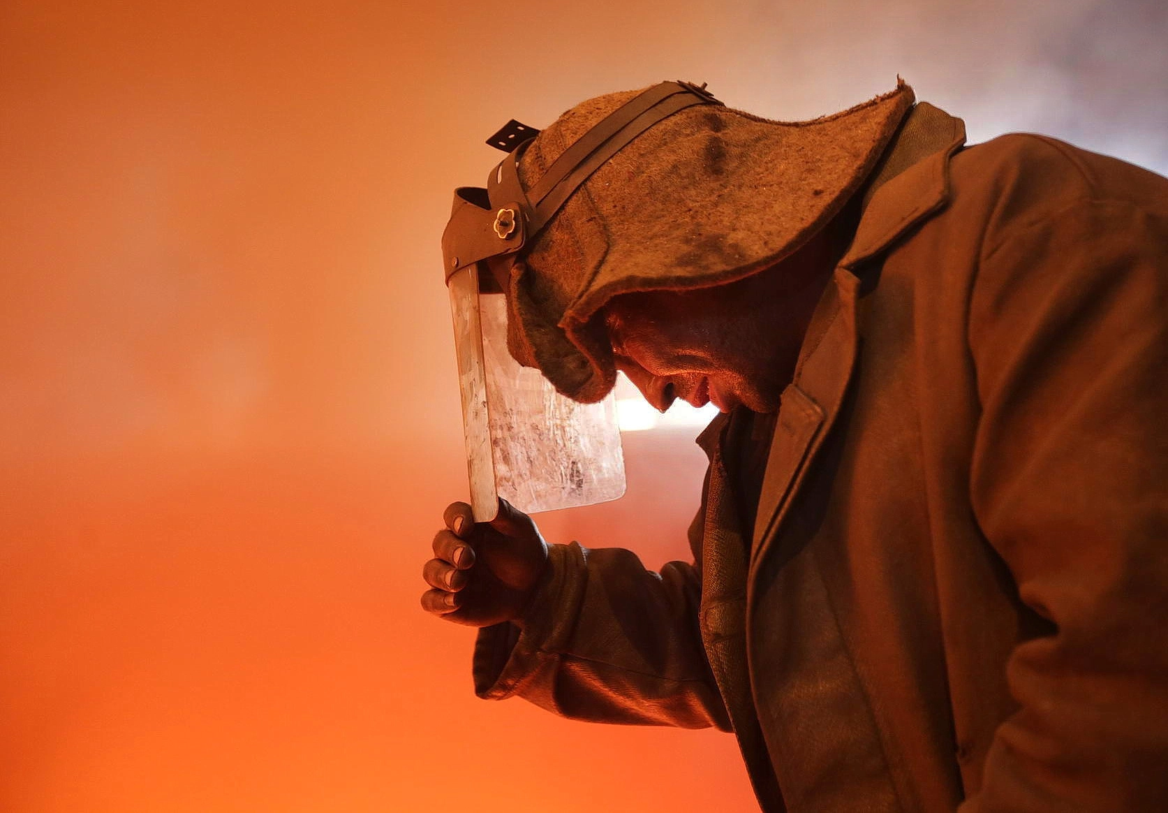 A steelworker dons a protective face guard at a blast furnace at ArcelorMittal Kryvyi Rih. 