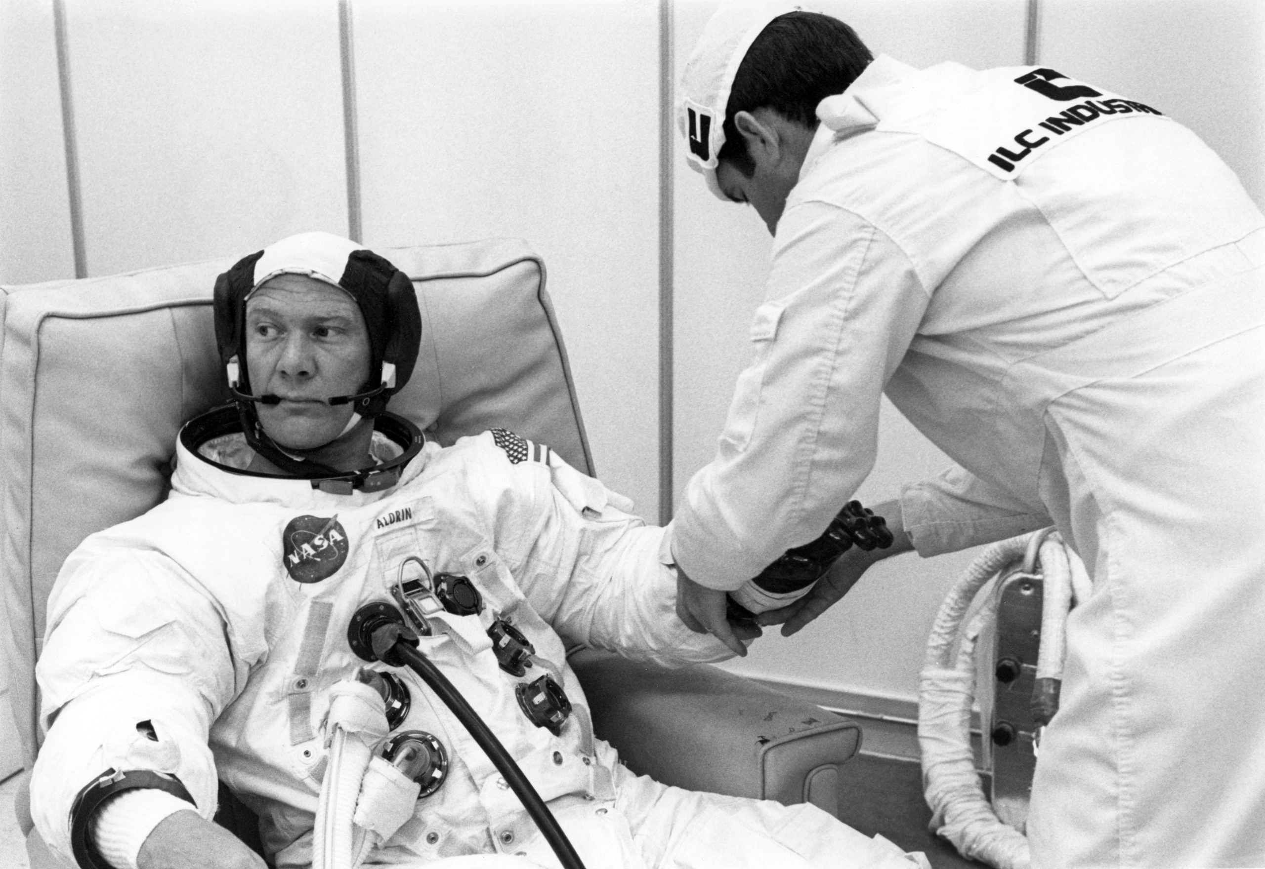 Suit technician Ron Woods (R) works on Buzz Aldrin (L) glove during suit-up on July 3, 1969