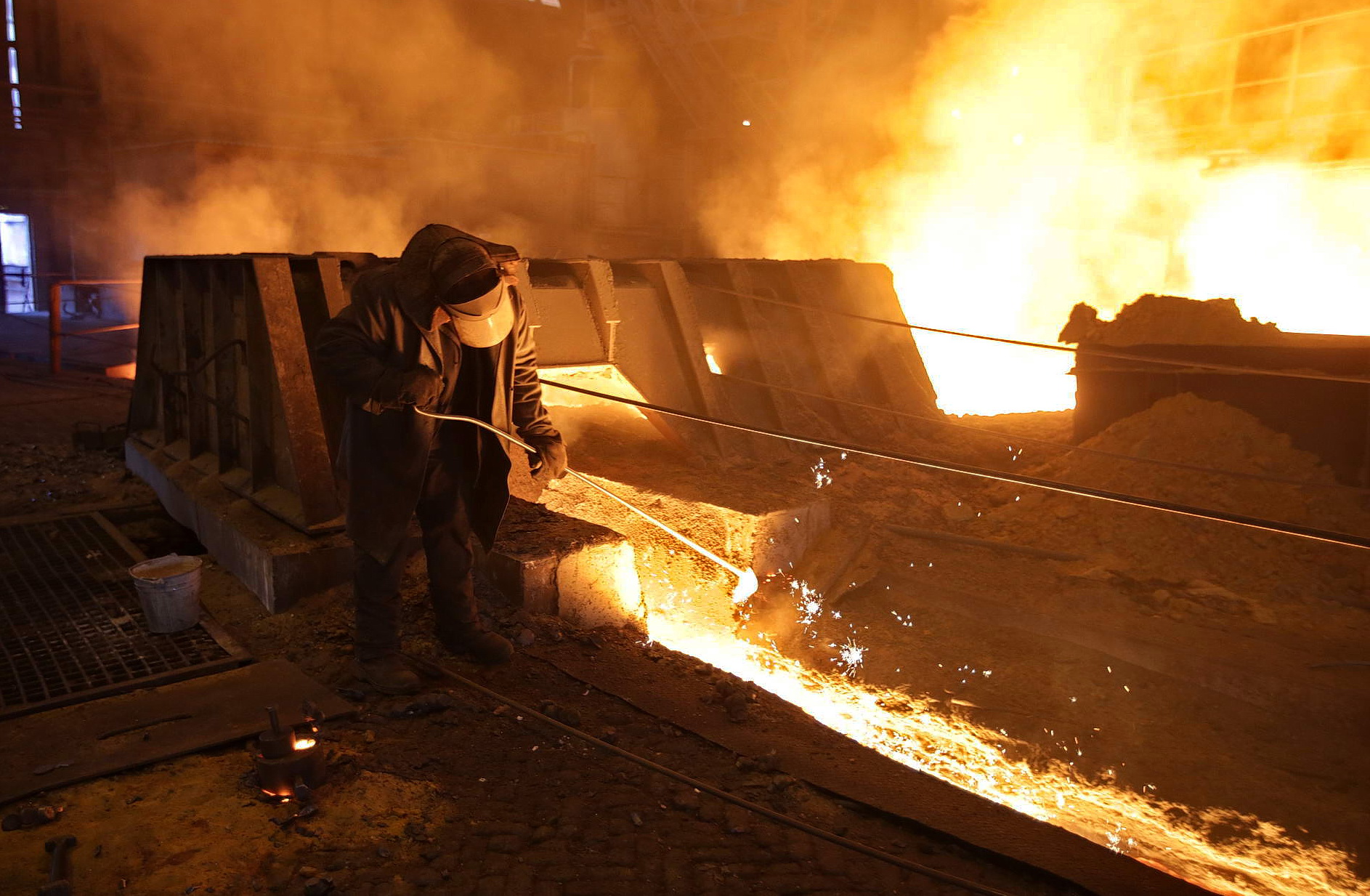 A steelworker inspects a flow of molten steel in a blast furnace at the ArcelorMittal Kryvyi Rih steel plant. 