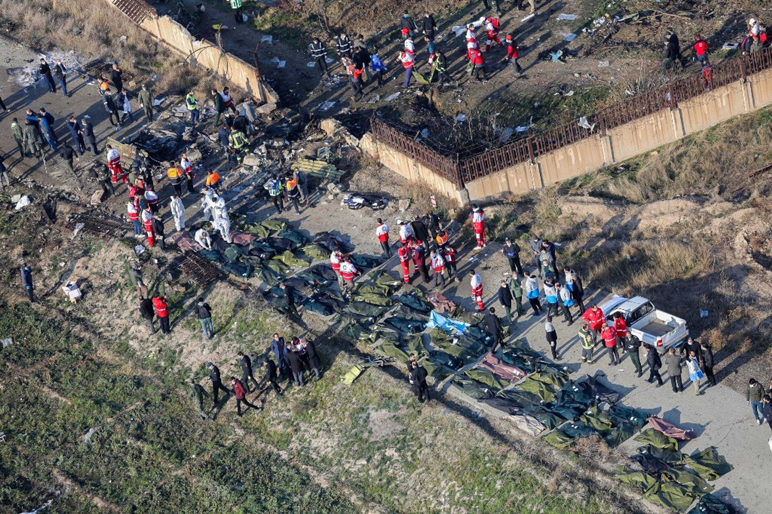 People and rescue teams are pictured amid bodies and debris after a Ukrainian plane carrying 176 passengers crashed near Imam Khomeini airport in the Iranian capital Tehran early in the morning on Jan. 8, 2020, killing everyone on board. 