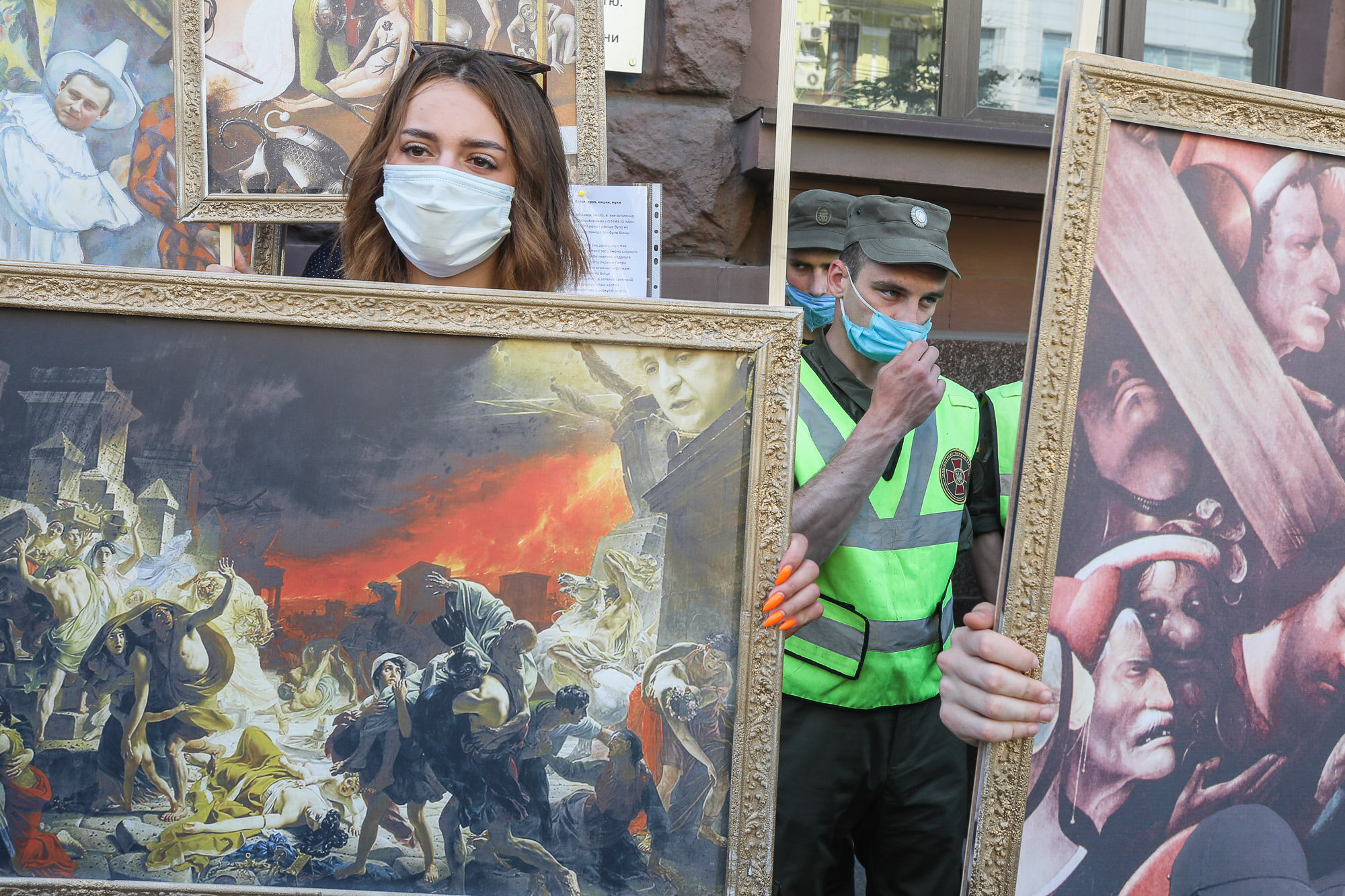 Activists and supporters of European Solidarity political party and Petro Poroshenko hold mockup pictures of classic art masterpieces with the faces of Prosecutor General Iryna Venediktova and President Volodymyr Zelensky during a rally in front of the State Investigation Bureau in downtown Kyiv on June 10, 2020.