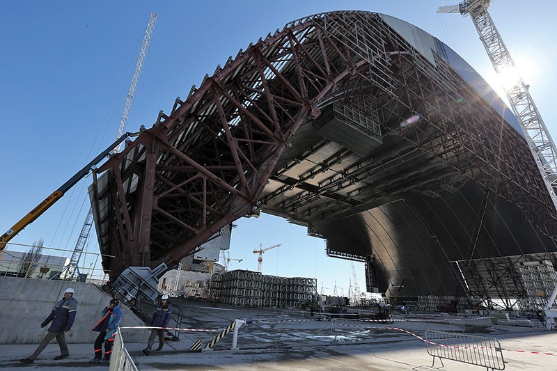 Workers walk in front of the new safe confinement at the Chornobyl nuclear power plant on March 17, 2016.