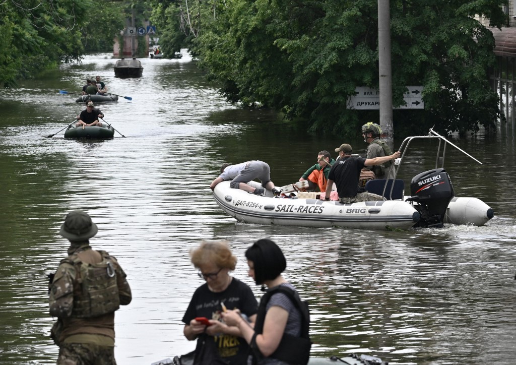 Ukrainian servicemen and volunteers sail on boats during an evacuation from a flooded area in Kherson on June 8, 2023.  Genya SAVILOV / AFP