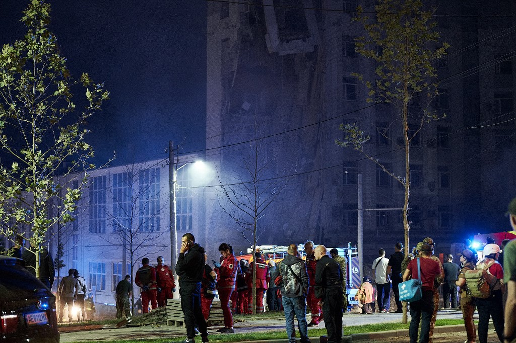 Rescuers stand outside a residential building partially destroyed after missiles strike in Dnipro on July 28, 2023. Vitalii  Matokha / AFP