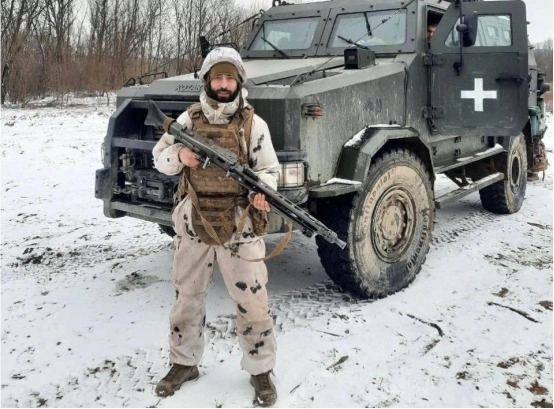 Soldier armed with a German machine gun poses next to a Ukrainian armored car, 71th Mountain Assault (formerly Jaeger) Brigade.