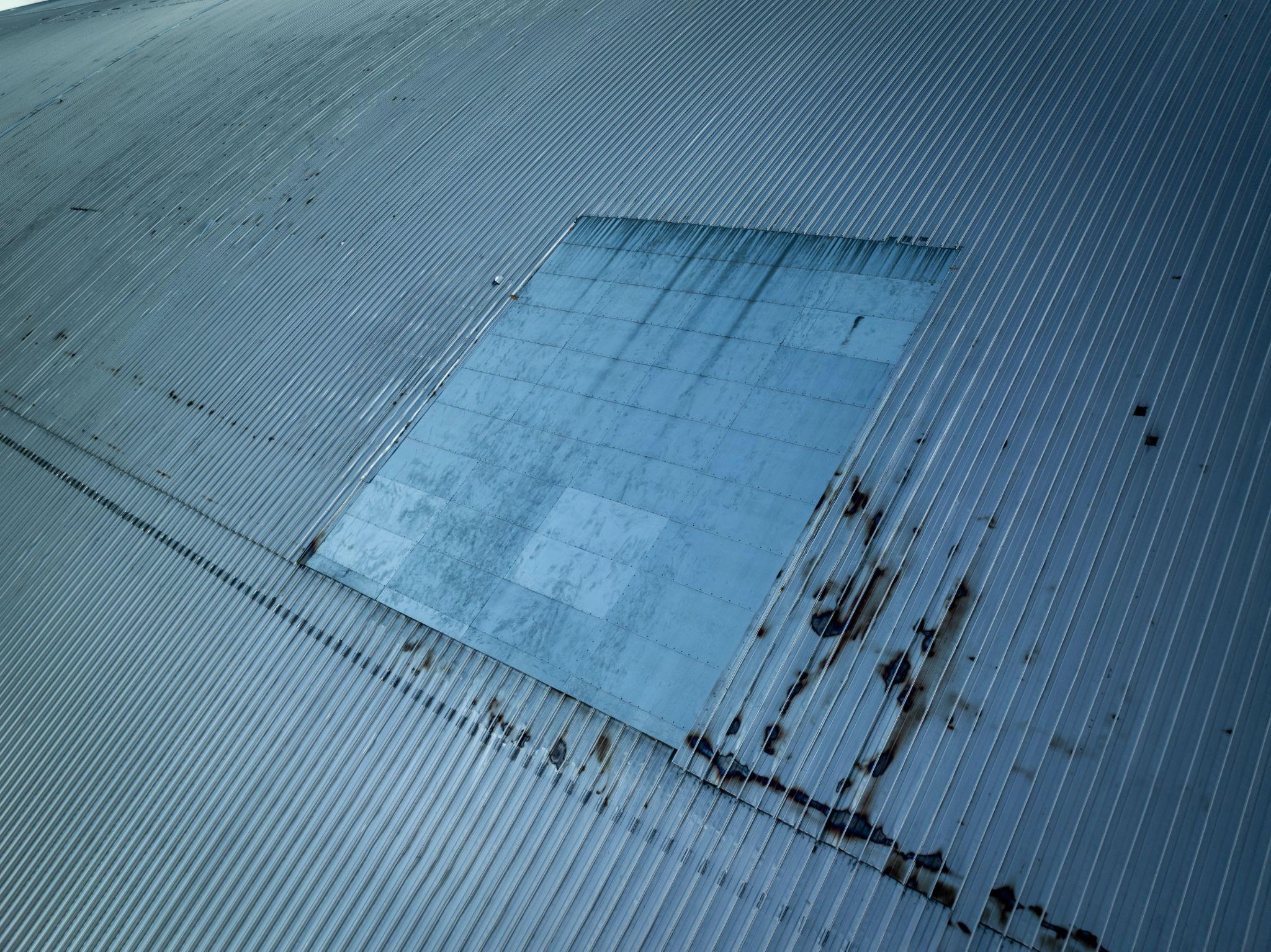 A hole in the cladding of the New Safe Confinement at the Chornobyl Nuclear Power Plant following a Russian drone strike on Feb. 14, 2025, and a temporary cover of the hole after the strike. (Photo courtesy of the EBRD press service)